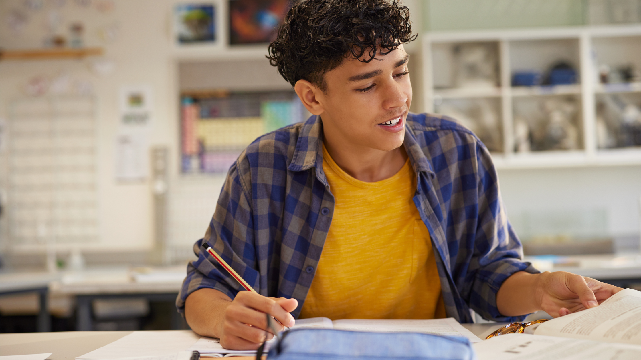 High school age boy in yellow shirt at desk applying to college