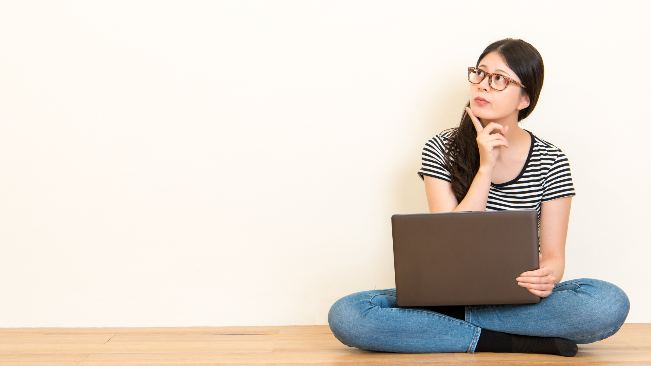 woman sitting on floor with laptop thinking about her grad school statement of purpose